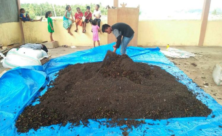 Salah seorang masyarakat Desa Konaweha sedang mengaduk bahan baku kompos sebelum diproses. (Foto: Zulfikar/SULTRAKINI.COM)