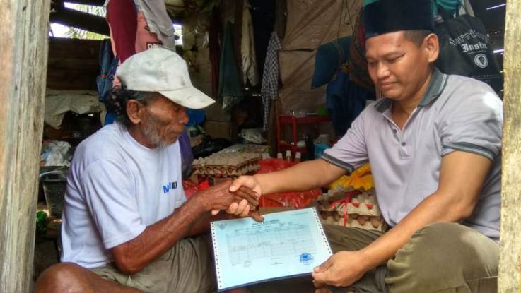 Kakek ompo saat menerima kartu keluarga yang diserahkan kepala desa setempat. ( Foto: Zhulfikar/ SULTRAKINI.COM)