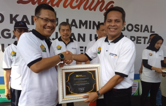 Deputi Direktur BPJS Ketenagakerjaan Wilayah Sulawesi Maluku, Sudirman Simamora saat memberikan penghargaan kepada Plt Walikota Kendari, Sulkarnain, Minggu (28/10/2018). (Foto: Hasrul Tamrin/SULTRAKINI.COM)