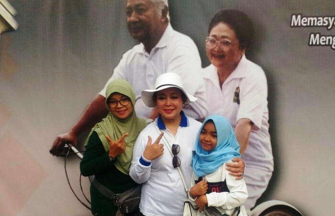 Poster besar Presiden Soeharto dan Ibu Tien bersepeda, dan orang-orang berebut berfoto di depannya bersama Siti Hediati Hariyadi. (Foto: Istimewa).
