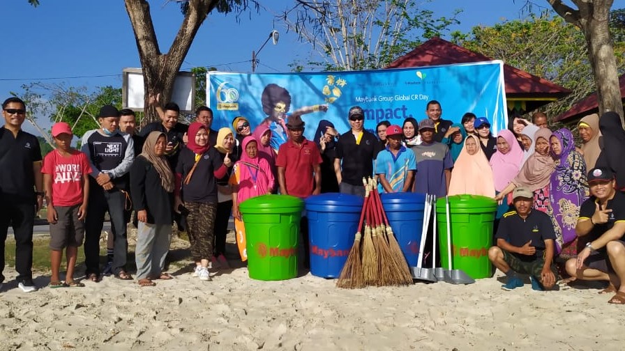 Karyawan Maybank Kendari foto bersama masyarakat usai melakukan aksi bersih-bersih di Pantai Nambo, Sabtu (25 Agustus 2019).