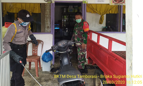 Bripka Sugianto Hutkri dan Sertu Deryas saat melakukan menyemprotan disinfektan di rumah warga Desa Tamborasi Kolaka, Sabtu (28/3/2020).