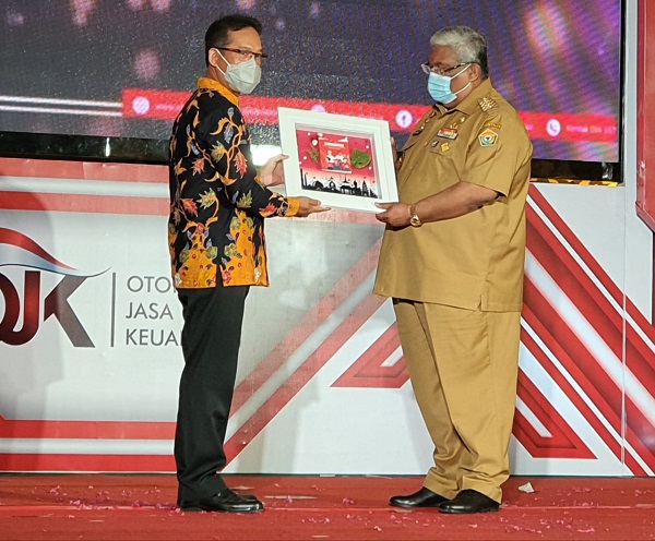 Kepala OJK Sultra, Mohammad Fredly Nasution (kiri) memberikan piagam penghargaan kepada Gubernur Sultra, Ali Mazi, pada acara Fusion di Kendari, Selasa (15 Desember 2020). Foto: Djufri/SultraKini.com