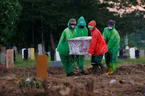 Petugas pemakaman membawa peti jenazah korban Covid-19 untuk dimakamkan. Foto: Reuters/Willy Kurniawan/AAP.