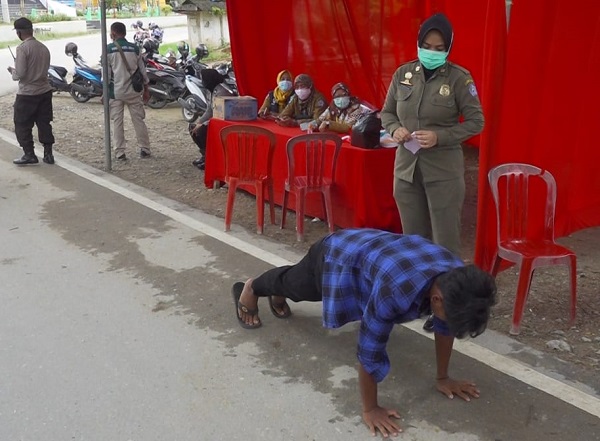 Salah seorang warga yang melanggar protokol kesehatan diberi sanksi push up oleh petugas Yustisi Kota Kendari. Foto: Diskominfo Kendari.