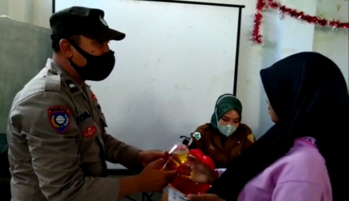 Kapolsek Wolio, Iptu Sunarton saat menyerahkan minyak goreng kepada peserta vaksinasi (Foto: Ist)